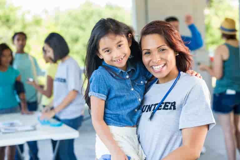 Smiling volunteer holding young girl